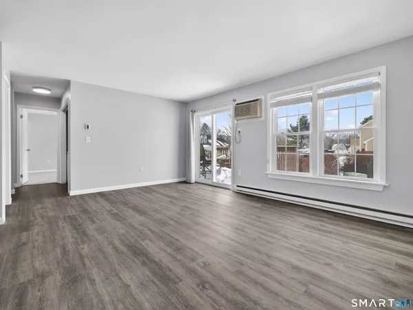 a view of an empty room with wooden floor and a window