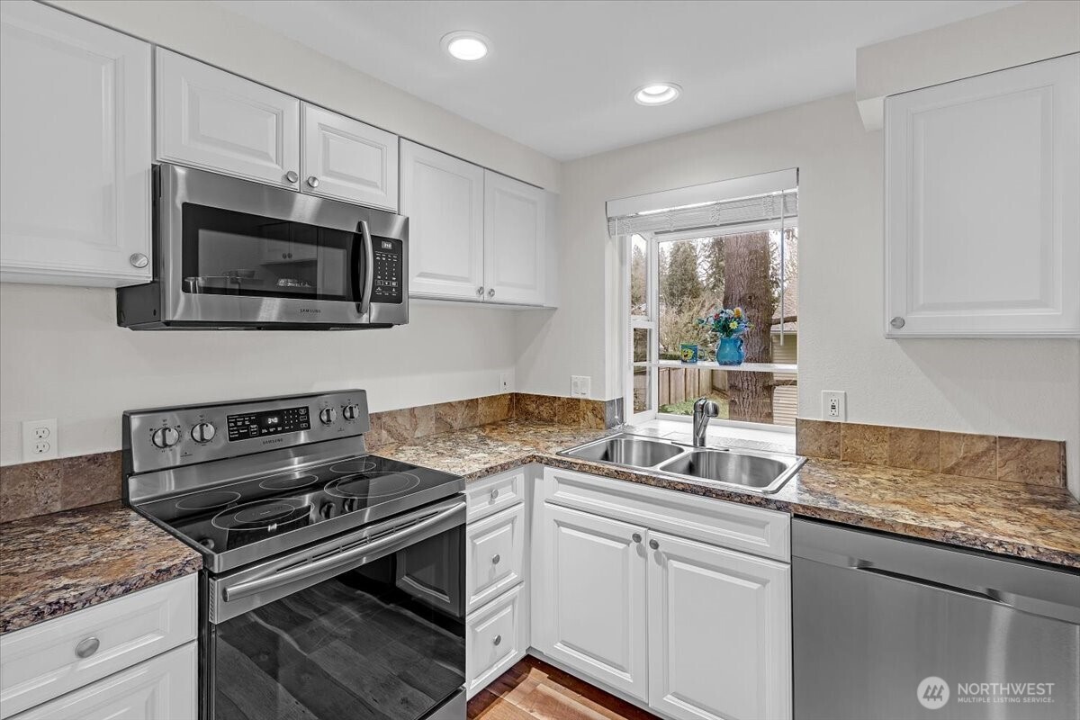 8653 Avondale Road Northeast, Unit D208 Redmond, WA 98052 - Photo 7 of 32 a kitchen with granite countertop a stove sink and microwave