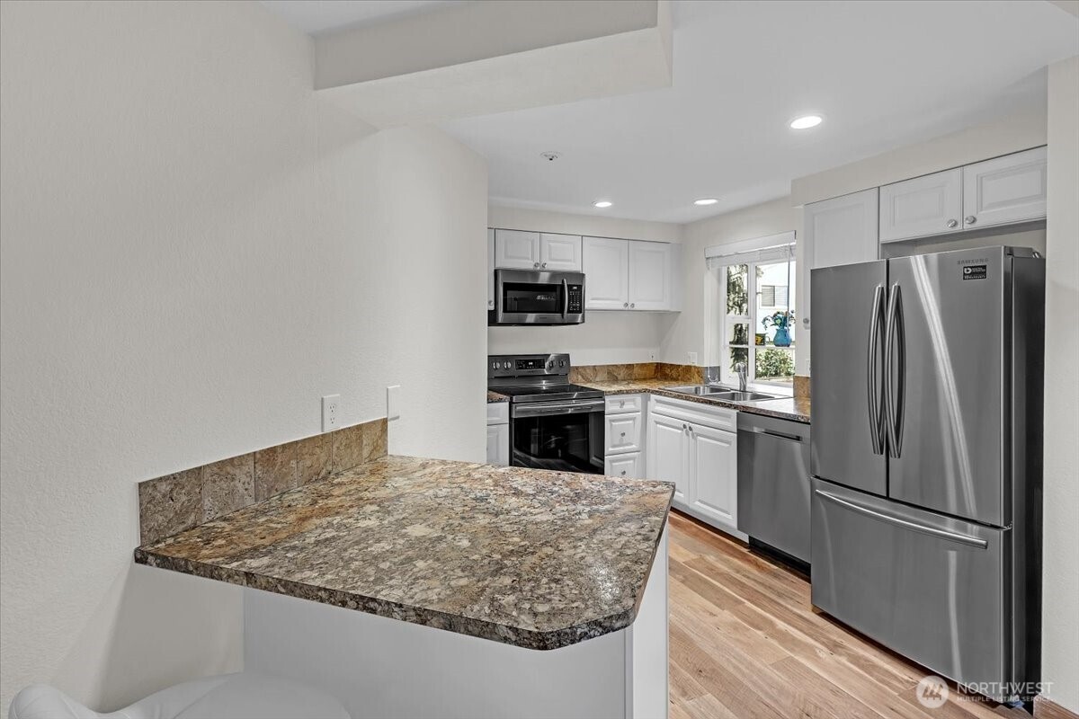 8653 Avondale Road Northeast, Unit D208 Redmond, WA 98052 - Photo 8 of 32 a kitchen with granite countertop a refrigerator oven a sink and dishwasher