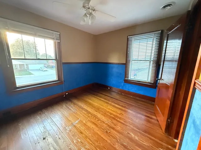 a view of empty room with wooden floor and fan