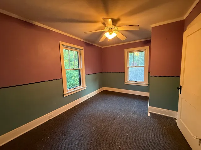 a view of an empty room with window and chandelier fan