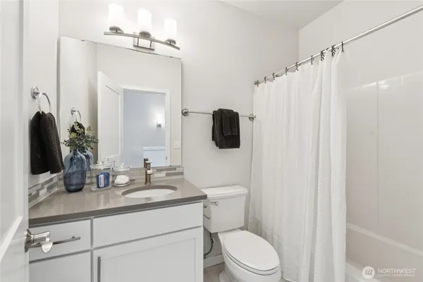 a bathroom with a granite countertop sink vanity mirror and toilet