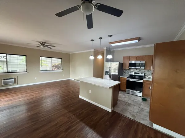 a kitchen with kitchen island wooden floors appliances and living room view