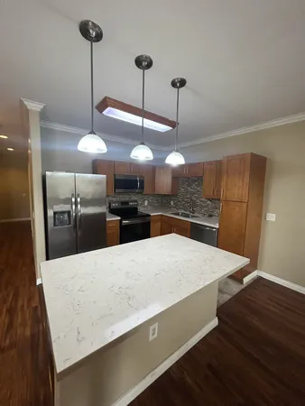 a large kitchen with stainless steel appliances a large counter top and refrigerator