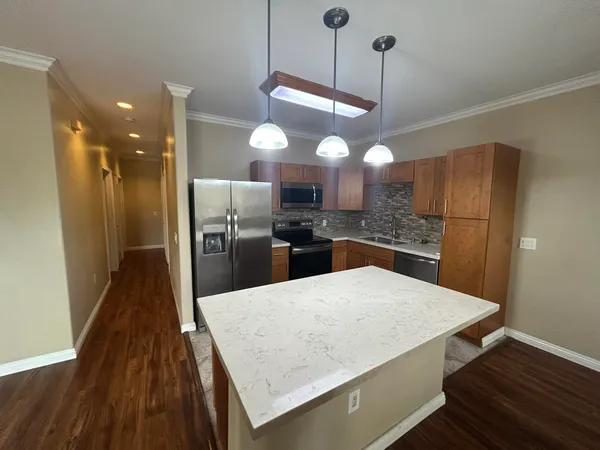 a kitchen with kitchen island a counter space a sink appliances and cabinets