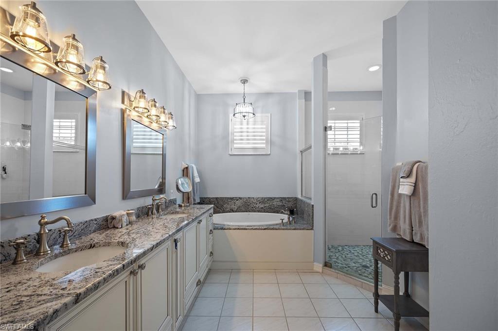 8943 Lely Island Circle Naples, FL 34113 - Photo 18 of 40 a bathroom with a granite countertop sink a toilet a mirror and bathtub