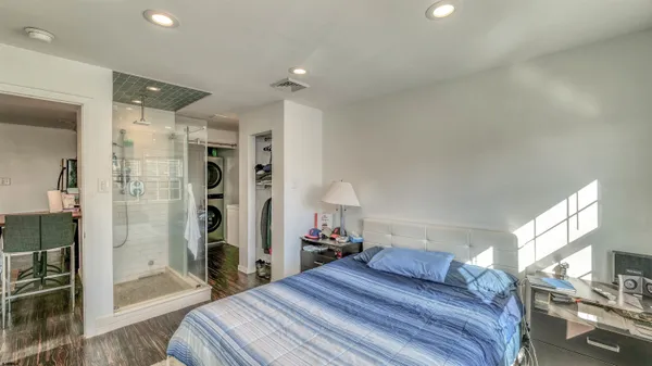 a bedroom with a large bed and a glass door shower