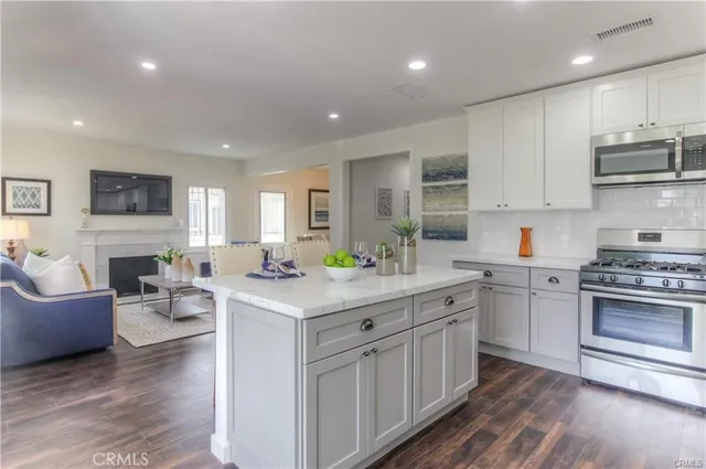 a kitchen with stainless steel appliances granite countertop a stove top oven a sink dishwasher and a refrigerator with wooden floor