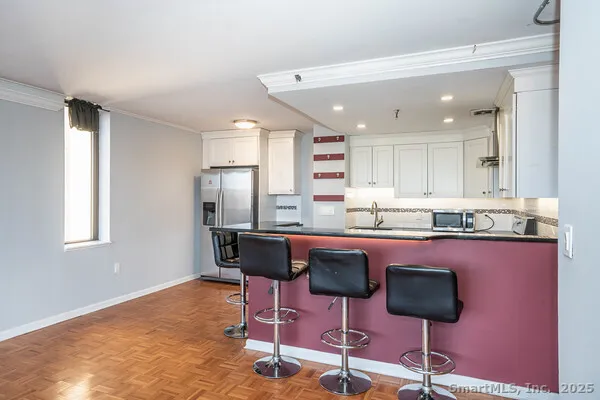 a kitchen with stainless steel appliances granite countertop a sink a stove a refrigerator with white cabinets and wooden floor