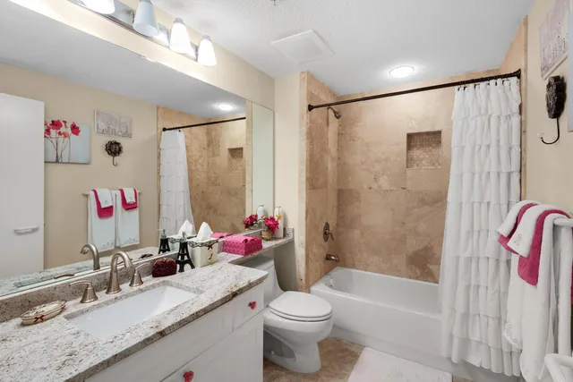 a bathroom with a granite countertop sink a mirror a vanity and shower