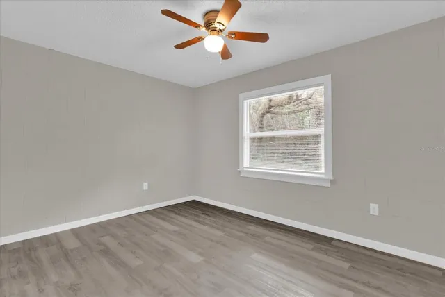 a view of empty room with wooden floor and fan