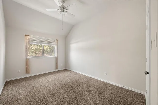 an empty room with a window and ceiling fan