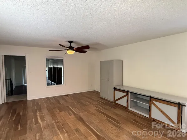 a view of an empty room with window and wooden floor