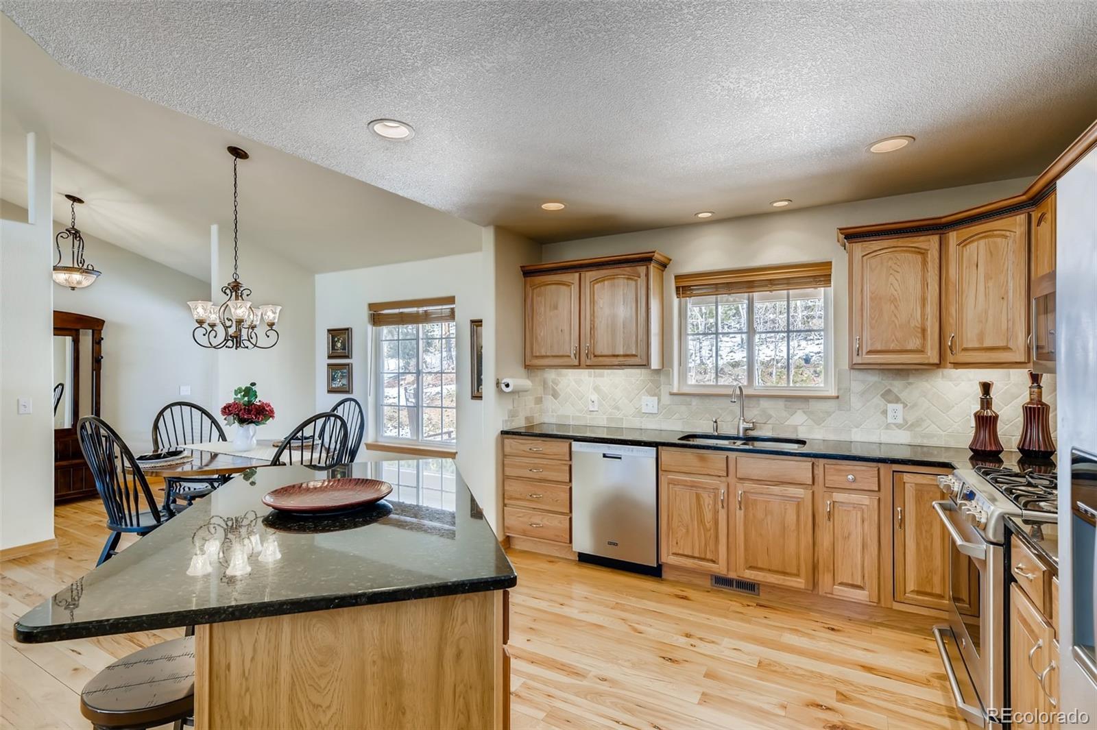35681 Upper Aspen Lane Pine, CO 80470 - Photo 9 of 36 a kitchen with kitchen island granite countertop a sink cabinets and wooden floor