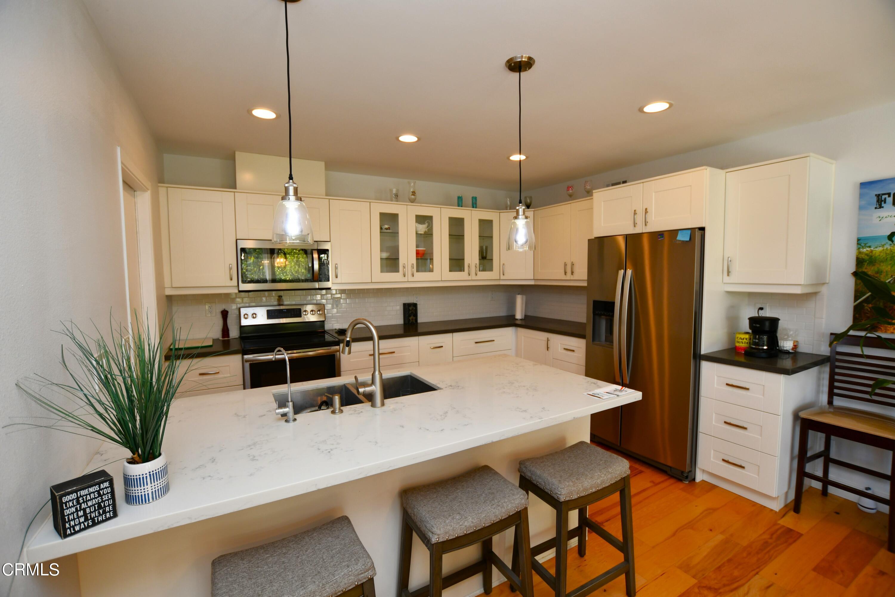 1711 Masthead Drive Oxnard, CA 93035 - Photo 5 of 18 a kitchen with stainless steel appliances a dining table chairs refrigerator and cabinets