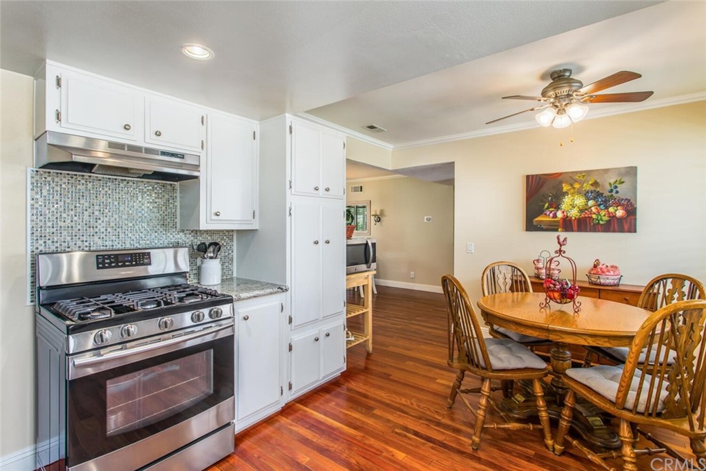 602 Juniper Court Redlands, CA 92374 - Photo 12 of 38 a kitchen with stainless steel appliances kitchen island granite countertop a table chairs stove and white cabinets