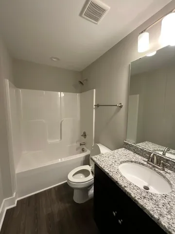 a bathroom with a granite countertop sink a toilet and shower