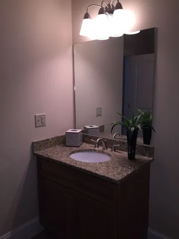 a bathroom with a granite countertop sink a mirror and vanity