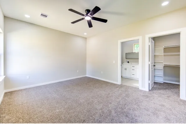 an empty room with closet and a ceiling fan