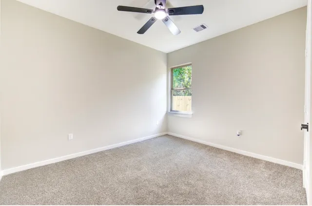 an empty room with a window and a fan