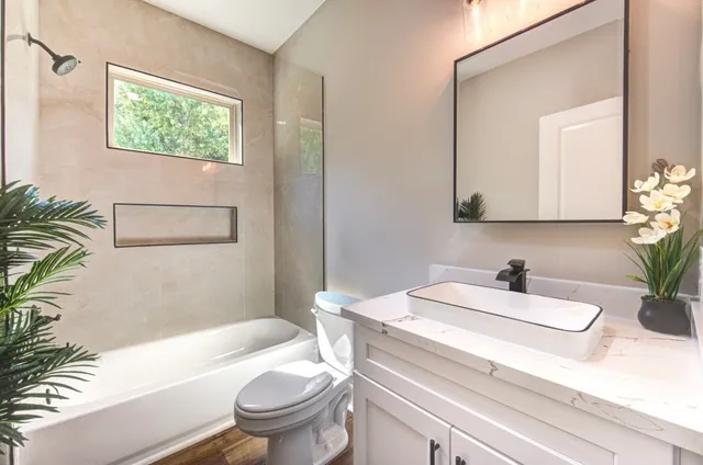 a bathroom with a sink a toilet a mirror and shower