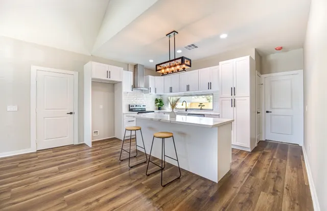 a kitchen with kitchen island white cabinets and stainless steel appliances
