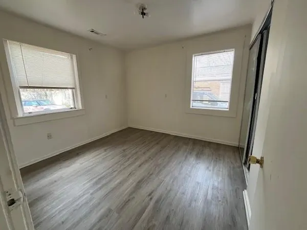 a view of an empty room with wooden floor and a window