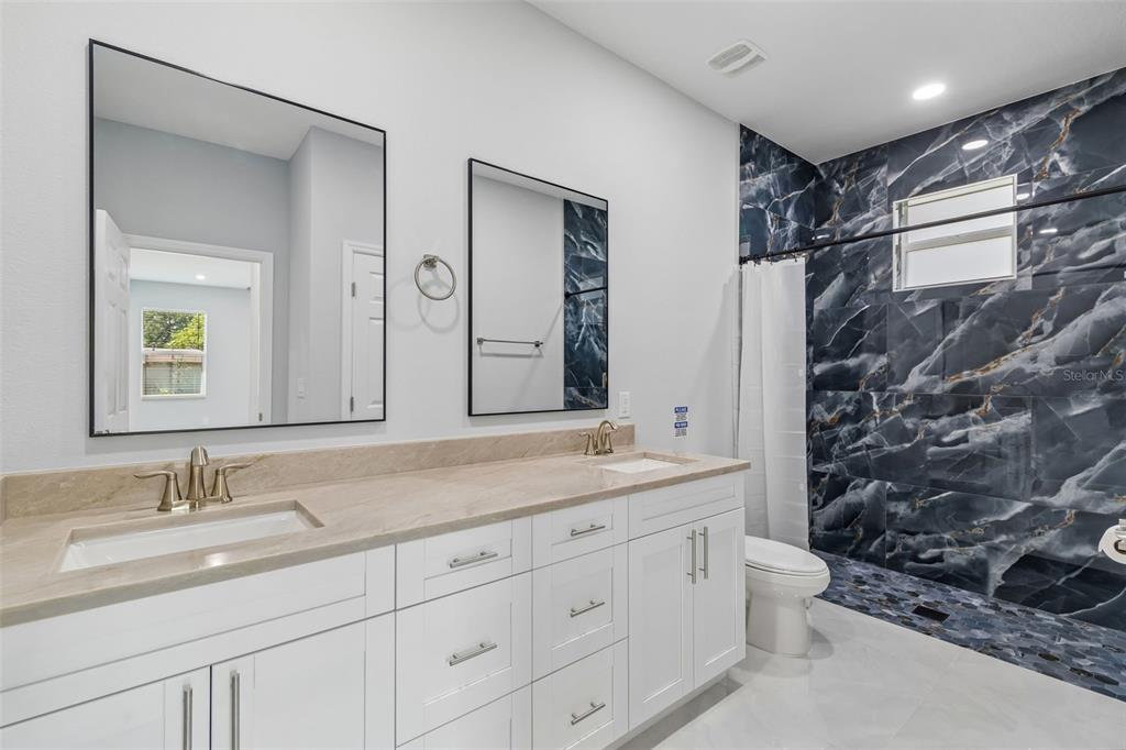 6018 Newmark Street Spring Hill, FL 34606 - Photo 13 of 26 a bathroom with a granite countertop sink a toilet and a shower