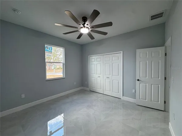 an empty room with windows and fan