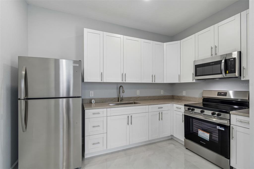 6018 Newmark Street Spring Hill, FL 34606 - Photo 22 of 26 a kitchen with appliances a sink and lots of cabinets