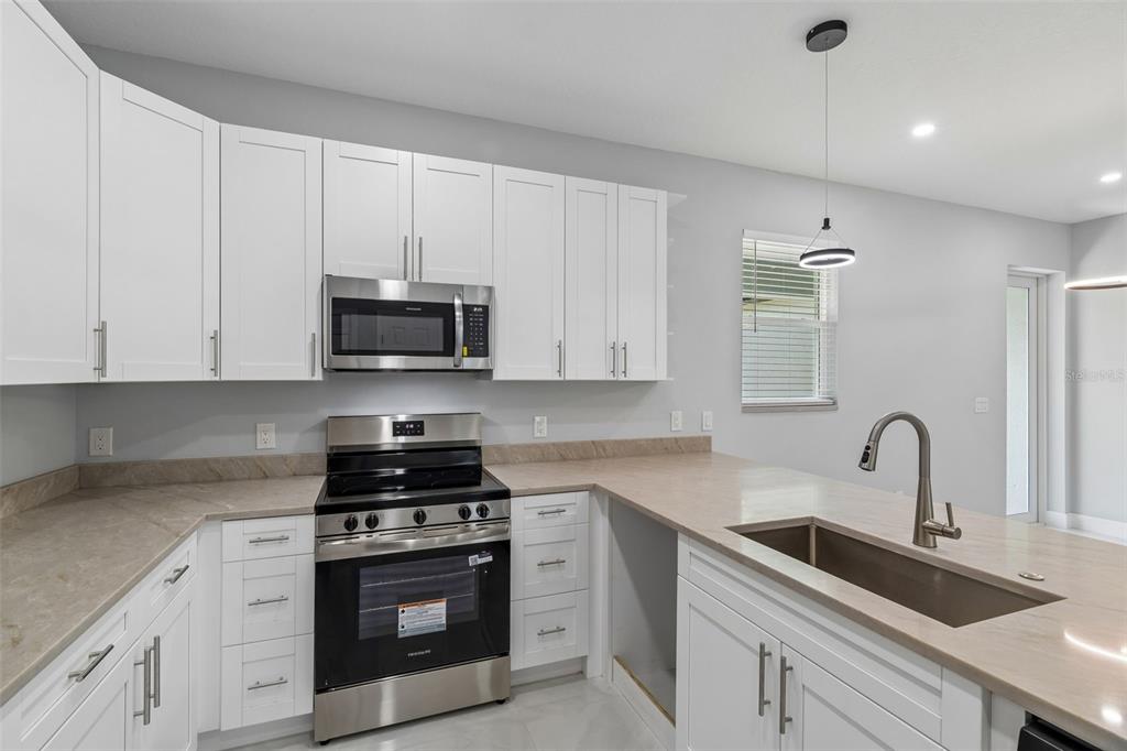 6018 Newmark Street Spring Hill, FL 34606 - Photo 6 of 26 a kitchen with white cabinets and stainless steel appliances