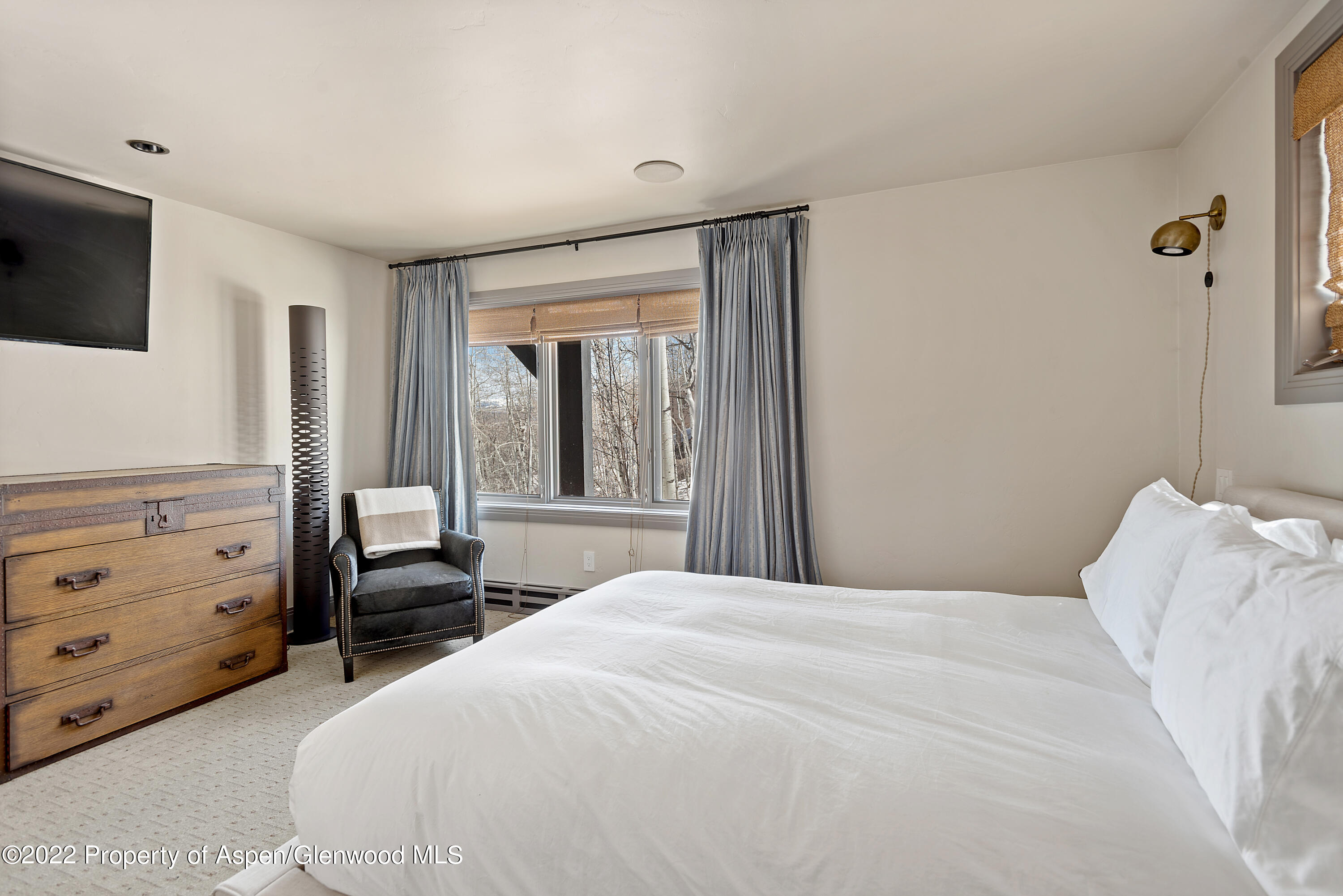 399 Maple Ridge Lane Snowmass Village, CO 81615 - Photo 19 of 27 a bedroom with a bed a flat tv screen and dresser