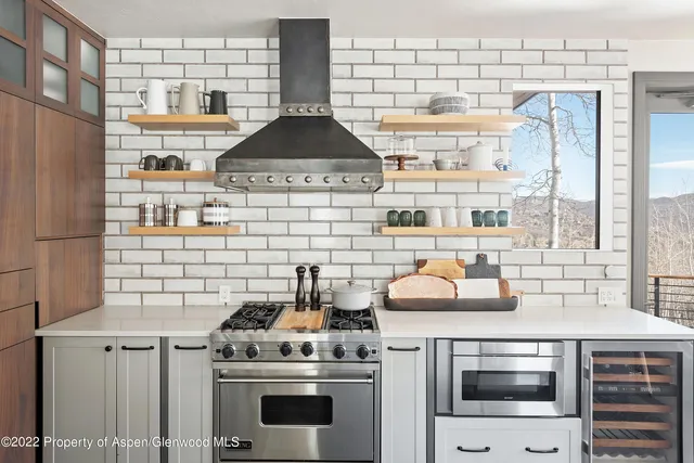 a kitchen with stainless steel appliances kitchen island granite countertop a table chairs and a refrigerator