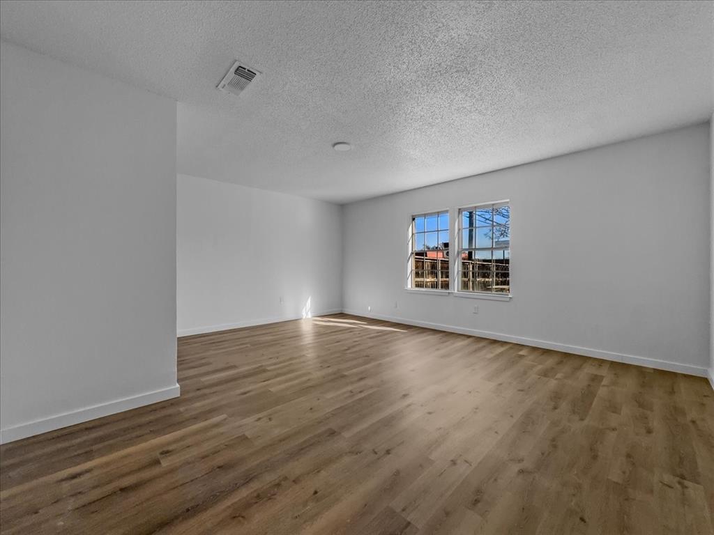 1236 Harrison Lane Hurst, TX 76053 - Photo 11 of 25 a view of an empty room with wooden floor and a window