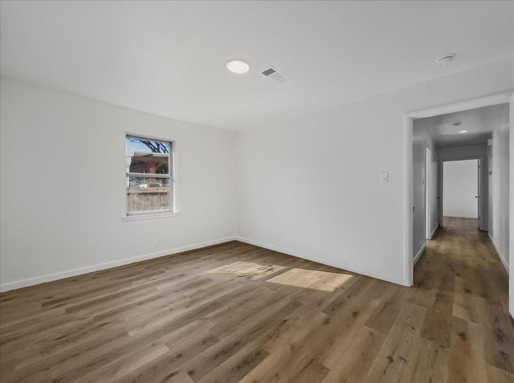 1236 Harrison Lane Hurst, TX 76053 - Photo 7 of 25 a view of an empty room with wooden floor and a window