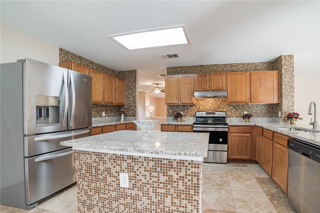 11228 Pickard Lane Austin, TX 78748 - Photo 9 of 32 a large kitchen with granite countertop a stove a sink dishwasher a refrigerator and cabinets with wooden floor