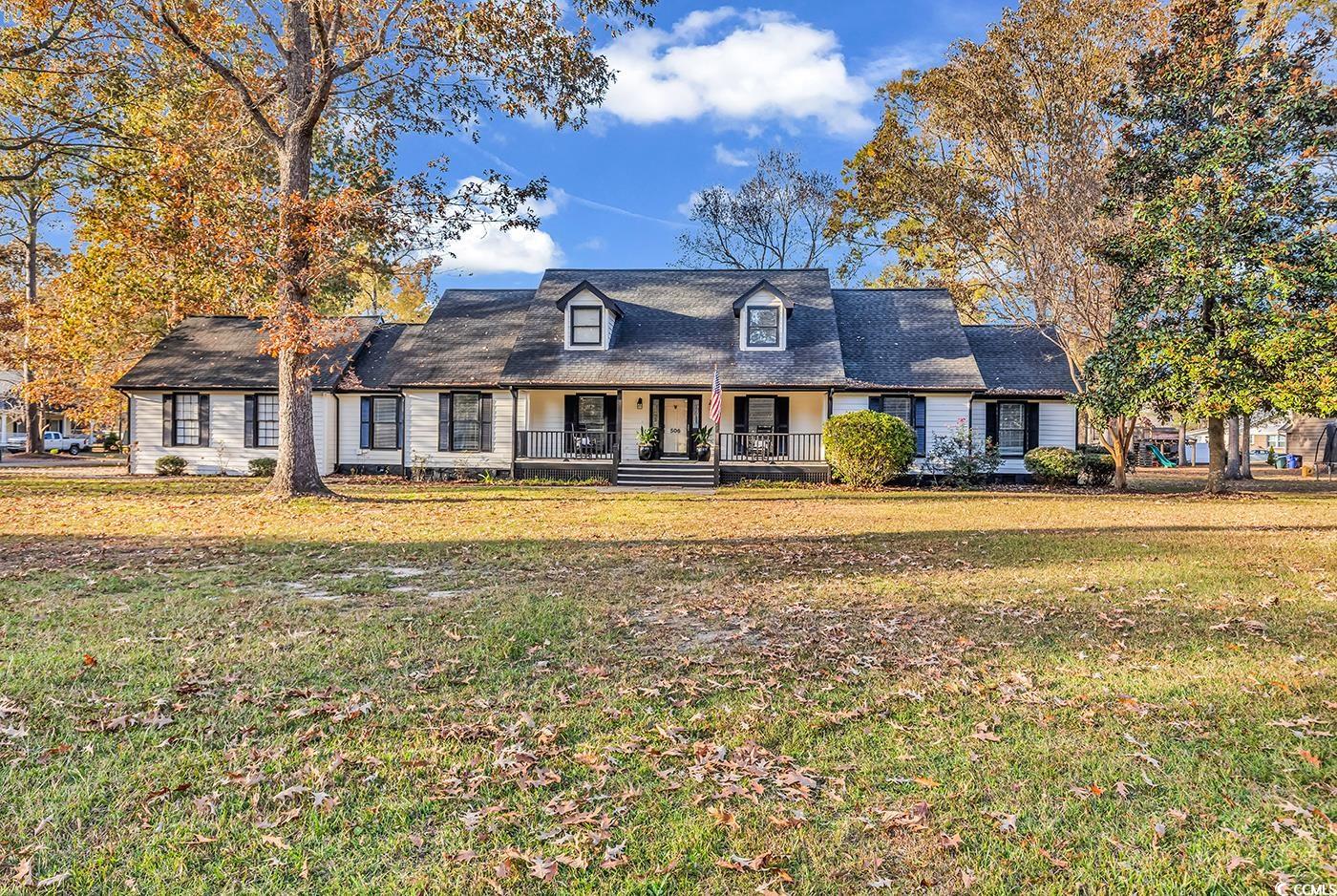 New england style home featuring covered porch and a front lawn