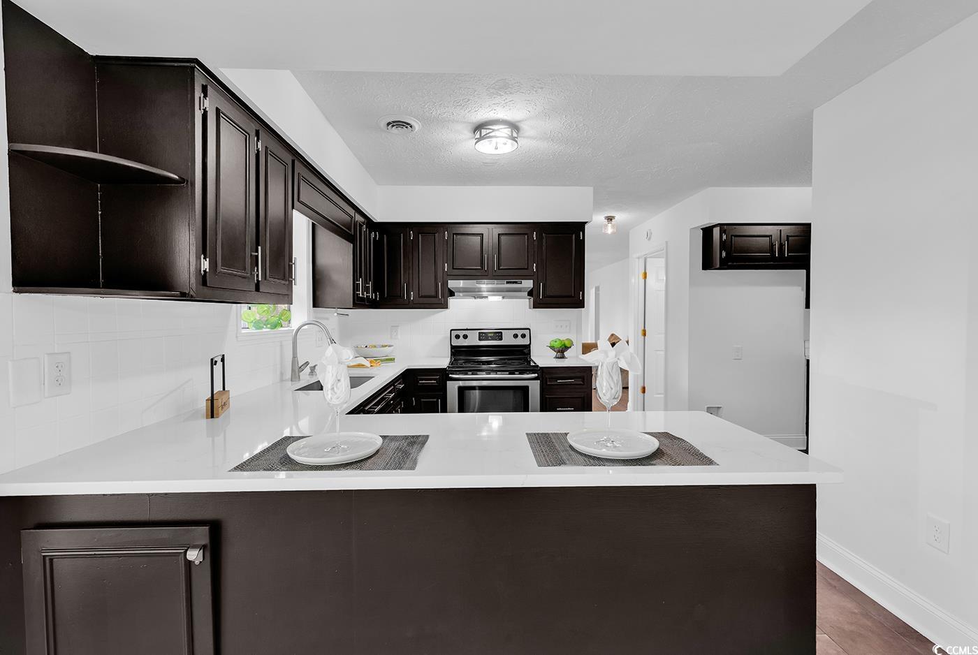 506 Merrywood Drive Conway, SC 29526 - Photo 12 of 40 Kitchen with open shelves, stainless steel range with electric stovetop, dark brown cabinets, a textured ceiling, and a peninsula