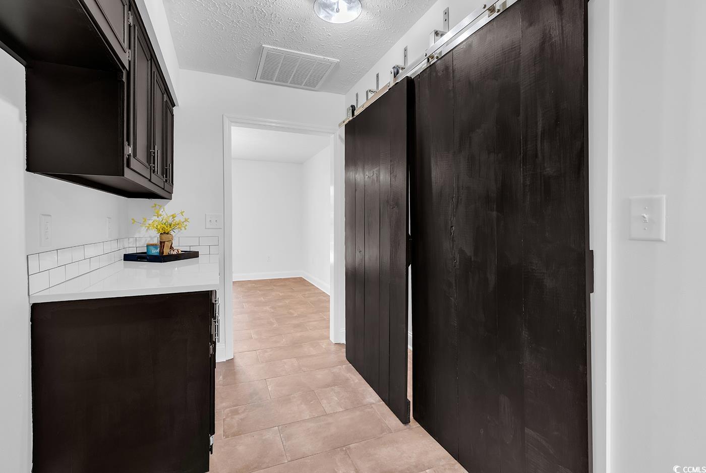 506 Merrywood Drive Conway, SC 29526 - Photo 8 of 40 Kitchen featuring a barn door, a textured ceiling, light stone counters, and dark brown cabinets