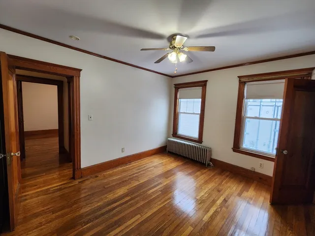an empty room with wooden floor chandelier and windows
