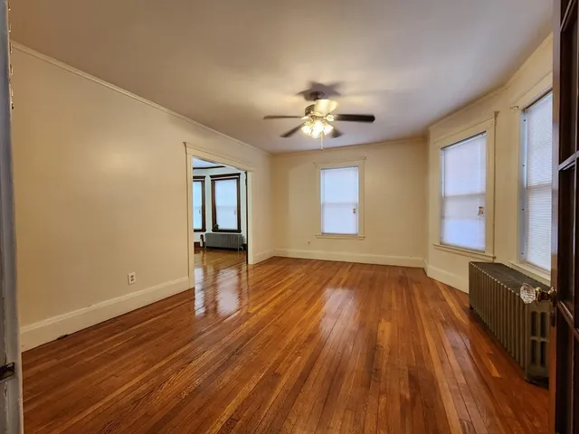 a view of an empty room with a window and wooden floor