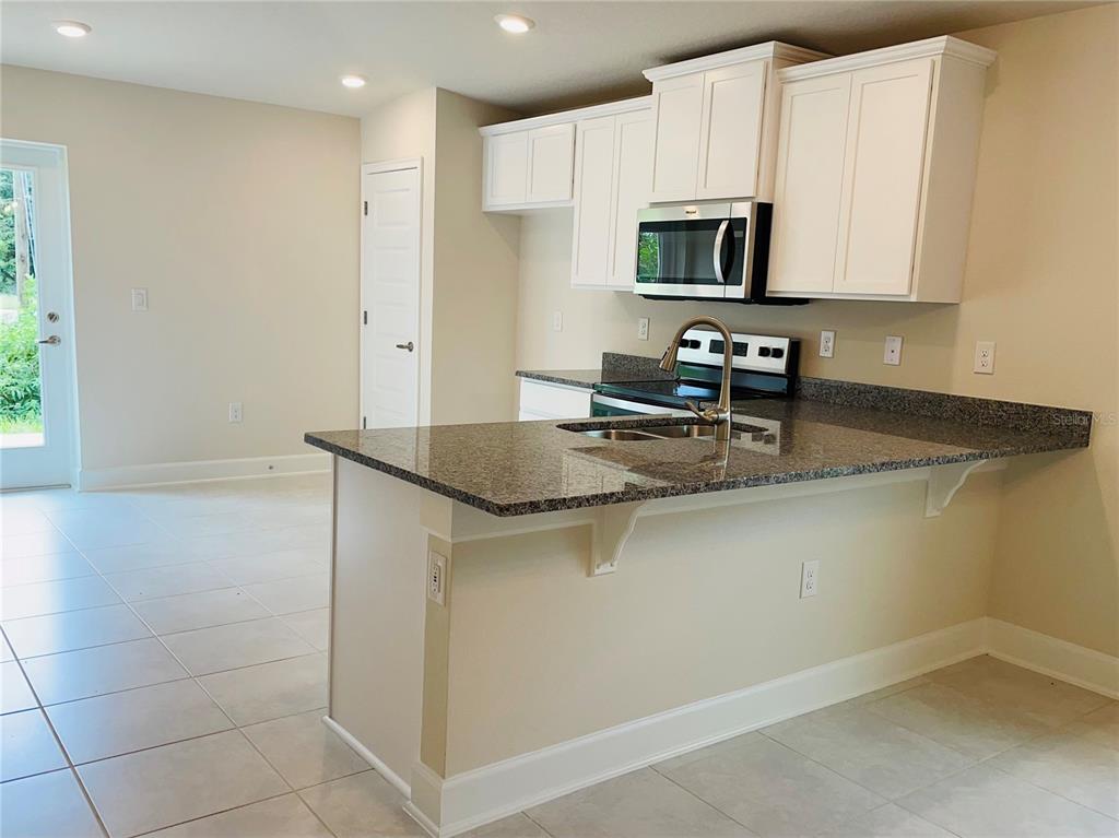 7625 Bent Tree Loop St. Cloud, FL 34773 - Photo 4 of 8 a kitchen with a sink a microwave and cabinets