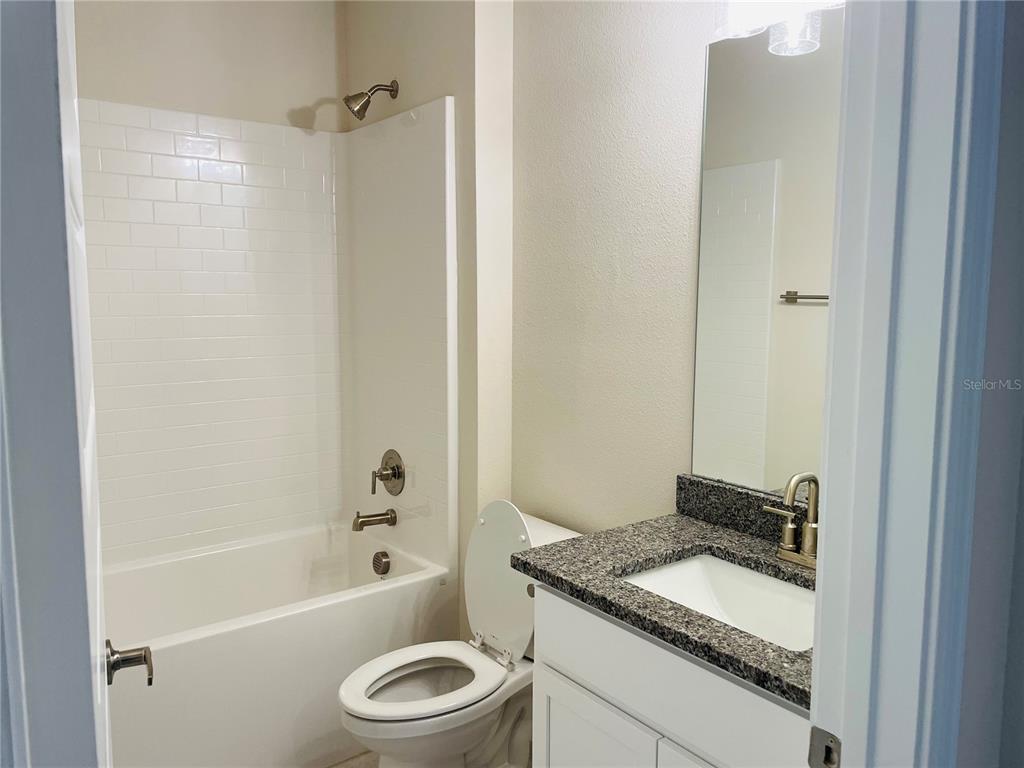7625 Bent Tree Loop St. Cloud, FL 34773 - Photo 7 of 8 a bathroom with a granite countertop sink toilet and shower