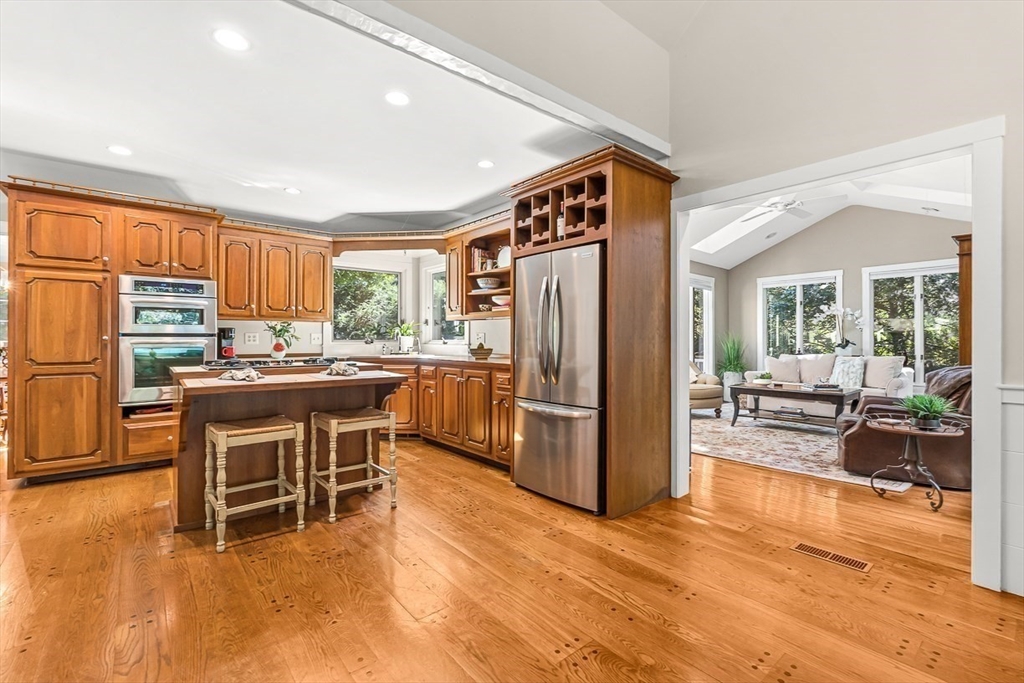 19 Louis Drive Wellesley, MA 02481 - Photo 7 of 30 a kitchen with a refrigerator a stove and a dining table with wooden floor