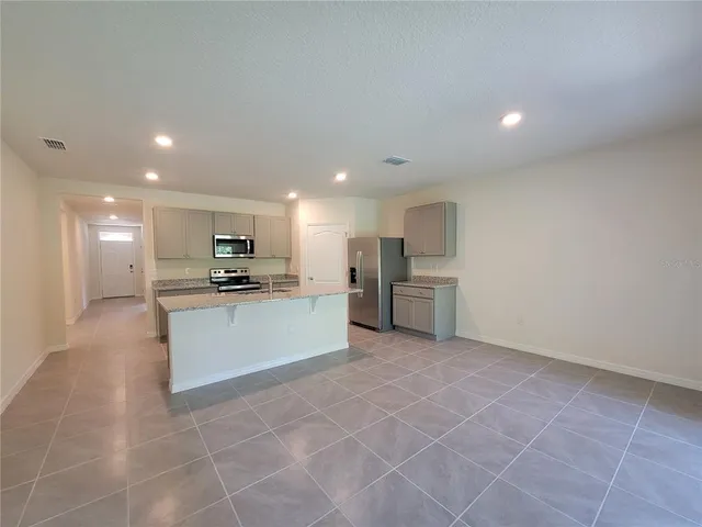 a large white kitchen with kitchen island a stove a sink a refrigerator and a cabinets