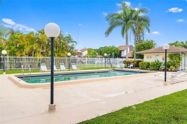 a view of a swimming pool with a lawn chairs under an umbrella