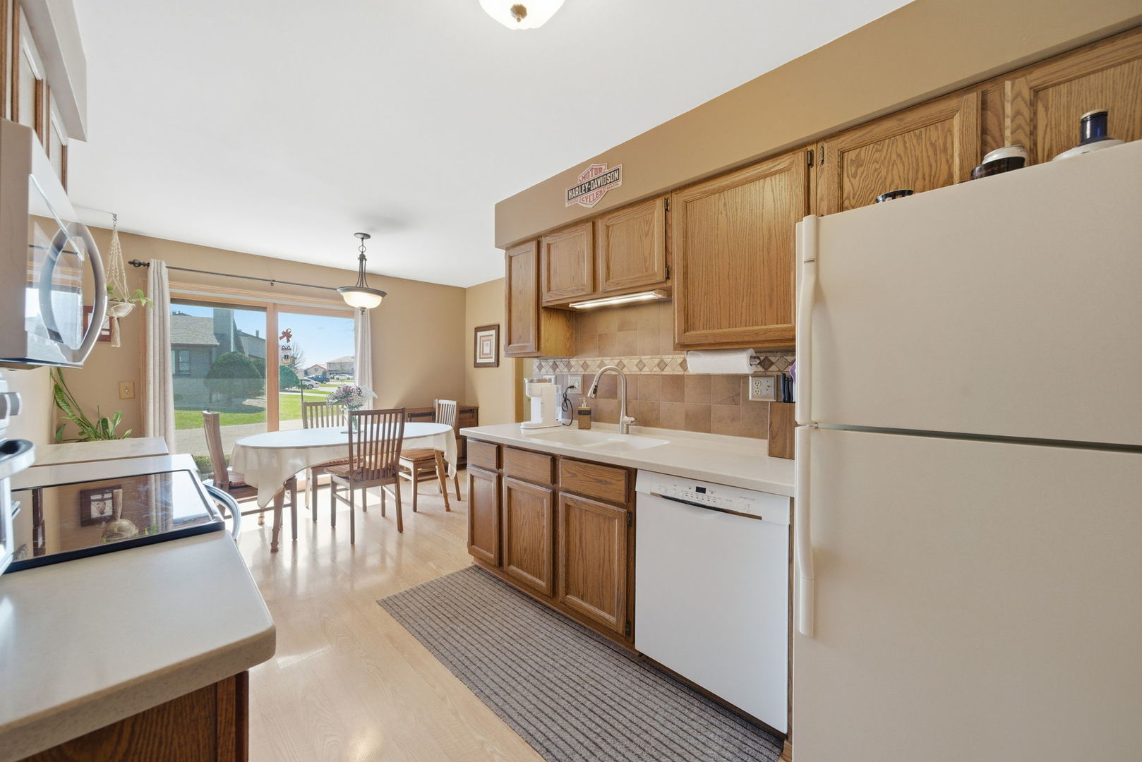 1839 Kerrybrook Court Sycamore, IL 60178 - Photo 2 of 25 a kitchen with a refrigerator a stove a sink and a dining table with wooden floor