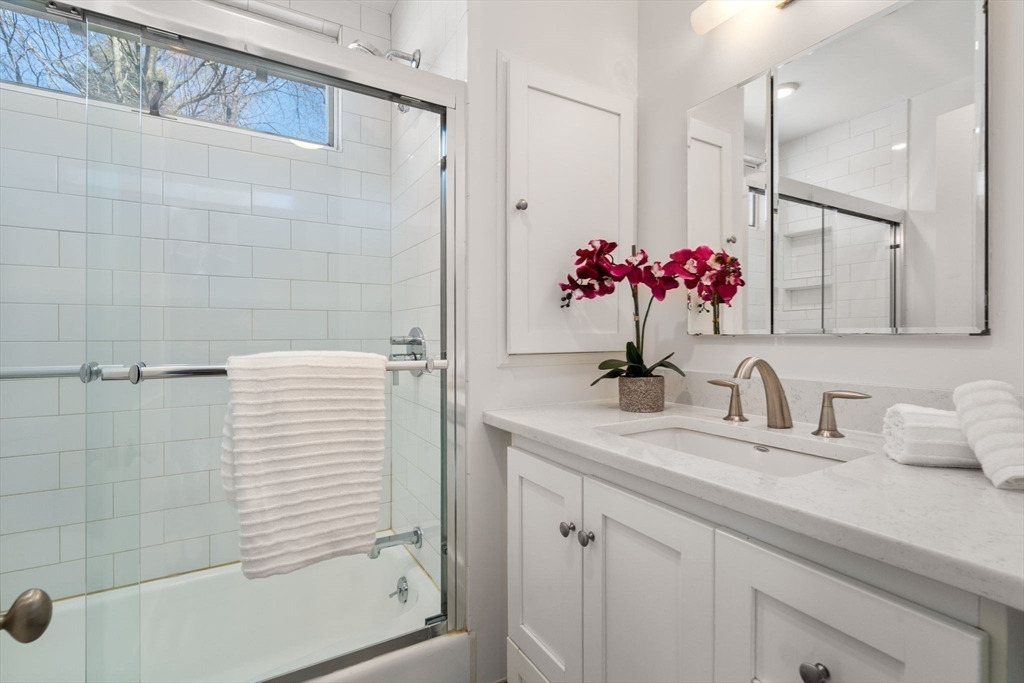 65 Bothfeld Road Newton, MA 02459 - Photo 17 of 31 a bathroom with a granite countertop sink a shower and a mirror