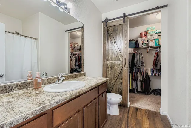 a bathroom with a granite countertop sink a toilet and a shower
