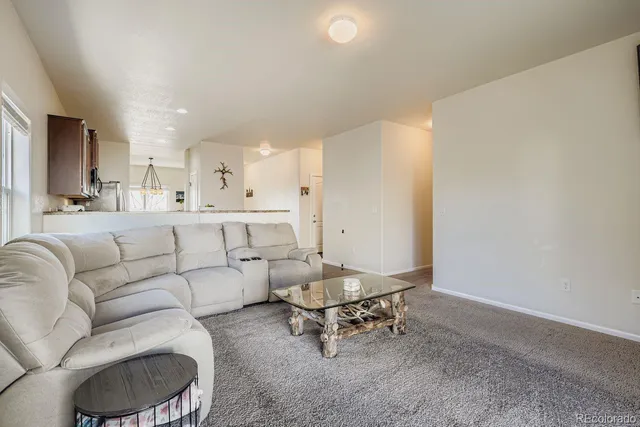 a living room with furniture and a dining table with kitchen appliances